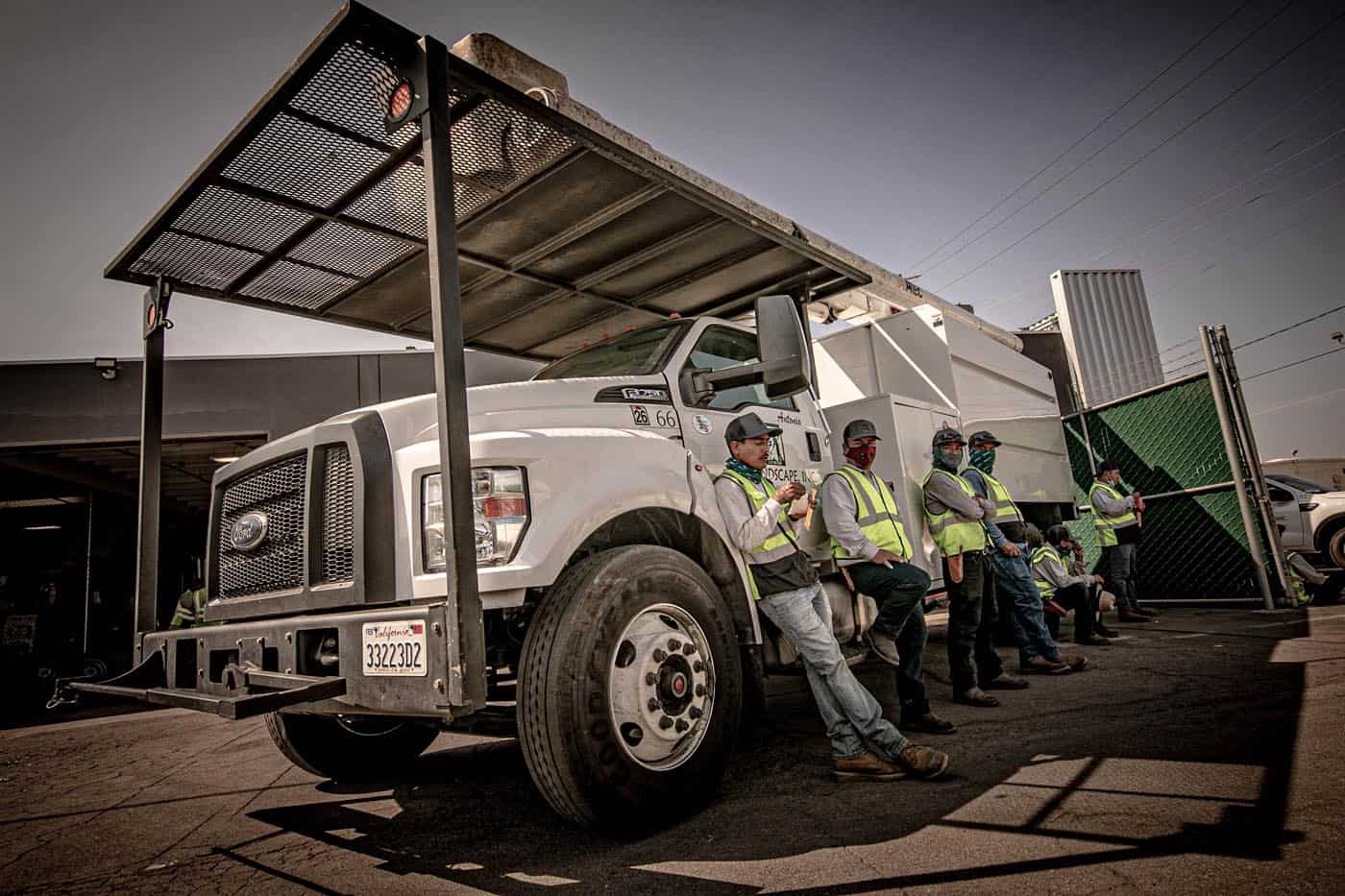 CG Landscape tree care crew in high-visibility vests beside a company truck